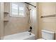 Bright bathroom featuring a white tub with a shower head, a window with shutters, and neutral beige tile at 3107 W Palmira Ave, Tampa, FL 33629