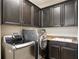 Well-equipped laundry room with dark cabinetry, granite countertops, sink and stainless steel washer and dryer at 3107 W Palmira Ave, Tampa, FL 33629