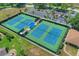 A high-angle view of well-maintained tennis courts next to a parking lot, showcasing the community's recreational amenities at 3124 Highlands Blvd, Palm Harbor, FL 34684