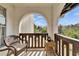 Cozy private balcony featuring an arched opening, wicker chair, and a small table with wooded outdoor view at 360 N Bayshore Blvd # 207, Clearwater, FL 33759