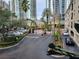 A paved driveway leading up to an entry gate with meticulously kept greenery, palm trees and high-rise apartments at 501 Knights Run Ave # 1113, Tampa, FL 33602