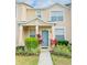 Two-story townhome with light beige exterior, landscaping, and teal door at 5010 Cactus Needle Ln, Wesley Chapel, FL 33544