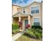 Two-story townhome with light beige exterior, landscaping, and teal door at 5010 Cactus Needle Ln, Wesley Chapel, FL 33544