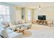 Bright living room featuring a comfortable sectional sofa, ottoman, and round wooden coffee table at 5010 Cactus Needle Ln, Wesley Chapel, FL 33544