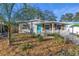 Charming bungalow with a teal door, white picket fence, and manicured landscaping at 6327 Emerson S Ave, St Petersburg, FL 33707