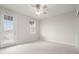 Bright, carpeted bedroom featuring a ceiling fan, a side door, and a window overlooking the backyard at 7602 S Desoto St, Tampa, FL 33616