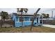 Side view of a light blue house with a grassy yard and palm trees at 7623 Gulf Blvd, St Pete Beach, FL 33706