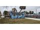 Front view of a light blue house with a grassy yard and palm trees at 7623 Gulf Blvd, St Pete Beach, FL 33706