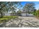 Gray house with a white garage door and a spacious driveway, surrounded by lush green landscaping at 1720 Hampton Ln, Clearwater, FL 33756