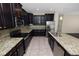 Modern kitchen with dark wood cabinets, granite counters, and stainless steel appliances at 18398 Aylesbury Ln, Land O Lakes, FL 34638