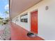 Side view of a condo building showcasing red doors and a red tiled walkway at 1950 58Th N Ave # 9, St Petersburg, FL 33714