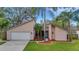 Tan house with white garage door, landscaping, and palm trees at 2826 Kavalier Dr, Palm Harbor, FL 34684