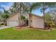 Tan house with a white garage door, palm trees, and a manicured lawn at 2826 Kavalier Dr, Palm Harbor, FL 34684