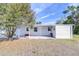 White mobile home with covered patio, storage, and mature tree at 37418 Hammond Dr, Zephyrhills, FL 33541