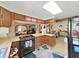 View of kitchen with wood cabinets, black appliances, and open view to dining area at 4001 Keene Rd, Plant City, FL 33565