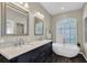 Elegant bathroom with double sinks, a soaking tub, and stylish dark wood cabinetry at 4996 Felecity Way, Palm Harbor, FL 34685