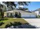 House exterior featuring a three-car garage and manicured lawn at 4996 Felecity Way, Palm Harbor, FL 34685