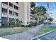 Exterior view of the condominium with palm trees and sidewalk, showcasing the building's design at 8950 Park Blvd # 406, Seminole, FL 33777