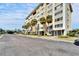 Low-angle view of a condominium building with large windows and palm trees lining the street at 8950 Park Blvd # 406, Seminole, FL 33777