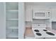 A view of the kitchen shows white cabinets, modern appliances, and open shelving for convenient storage at 8950 Park Blvd # 406, Seminole, FL 33777