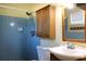Bathroom featuring blue tiled walls, overhead storage, and mirror over the sink at 1322 Kenmore St, Port Charlotte, FL 33952