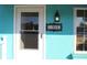 Charming aqua home exterior with decorative house number plaque and white-framed entry door with screen at 1322 Kenmore St, Port Charlotte, FL 33952