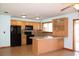 Open kitchen featuring wood cabinets, black appliances, tile backsplash, and a functional breakfast bar at 1322 Kenmore St, Port Charlotte, FL 33952