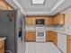 Kitchen with wood cabinets, white appliances, and tile floors at 134 Mariner Dr # 134, Tarpon Springs, FL 34689