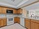 Kitchen with wood cabinets, white appliances, and tile floors at 134 Mariner Dr # 134, Tarpon Springs, FL 34689