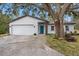 Two-car garage, teal front door, and mature landscaping at 1399 Grapeleaf Ct, Tarpon Springs, FL 34689