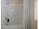 Clean bathroom features a bathtub-shower combination with a striped shower curtain, and white tiled walls at 15555 Martinmeadow Dr, Lithia, FL 33547
