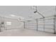 Spacious three-car garage with ample lighting, pristine white walls, and epoxy flooring for easy maintenance at 15555 Martinmeadow Dr, Lithia, FL 33547