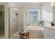 Bright and airy main bathroom showcases a soaking tub, separate shower, and a large window at 15555 Martinmeadow Dr, Lithia, FL 33547