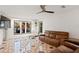 Bright living room features decorative tile floor, brown leather sofa, and a picturesque view of the outdoor pool area at 403 Weeburn Rd, Temple Terrace, FL 33617