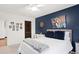 Main bedroom with navy accent wall, white bedding, and a dark wood door at 403 Weeburn Rd, Temple Terrace, FL 33617