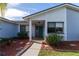 Front entrance with a teal door, covered porch, and nicely landscaped walkway at 4726 Windflower Cir, Tampa, FL 33624