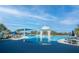 Community pool with clear blue water, surrounding lounge chairs, shaded tables, and a decorative center gazebo at 4748 Ballast Crest Cv, Land O Lakes, FL 34638