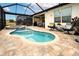 Screened-in pool area features a spa, patio seating, and well-maintained landscaping at 4748 Ballast Crest Cv, Land O Lakes, FL 34638