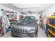 A well-lit garage featuring a gray SUV, storage shelves, and overhead garage door at 5405 Golden Nugget Dr, Holiday, FL 34690