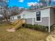 Mobile home exterior with gray and white siding, a wooden staircase, and landscaping at 13017 Manatee Ave, New Port Richey, FL 34654