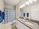 Bathroom boasts a double vanity, shower/tub combo, and blue patterned shower curtain at 16959 Scuba Crest St, Wimauma, FL 33598