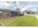 Spacious backyard with a screened lanai, lush grass, and white picket fence at 6722 Boulder Run Loop, Wesley Chapel, FL 33545