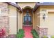 Inviting front entrance showcasing double doors, stone accents, manicured greenery, and a vibrant red walkway at 6722 Boulder Run Loop, Wesley Chapel, FL 33545