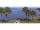Waterfront backyard features lush green grass, shady palm trees, an umbrella, and a picnic table with benches at 100 Bluff View Dr # 401A, Belleair Bluffs, FL 33770