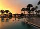 Community pool overlooking the ocean, lined with palm trees, lounge chairs, and a ladder to enter the pool at 100 Bluff View Dr # 401A, Belleair Bluffs, FL 33770