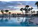 Community pool overlooks the water, lined with palm trees, and features lounge chairs for relaxing by the water at 100 Bluff View Dr # 401A, Belleair Bluffs, FL 33770
