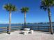 Waterfront view featuring a dock with a picnic table and a bench between large palm trees overlooking the water at 100 Bluff View Dr # 401A, Belleair Bluffs, FL 33770