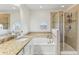Bathroom featuring a tub, walk-in shower, granite countertops, and a round window at 10144 Arbor Run Dr # 107, Tampa, FL 33647