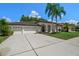White house with dark brown roof, 3-car garage, and palm trees at 1257 Kings Way Ln, Tarpon Springs, FL 34688