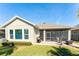 Tan house with 3-window elevation, screened patio, and landscaped yard at 14015 Kingfisher Glen Dr, Lithia, FL 33547